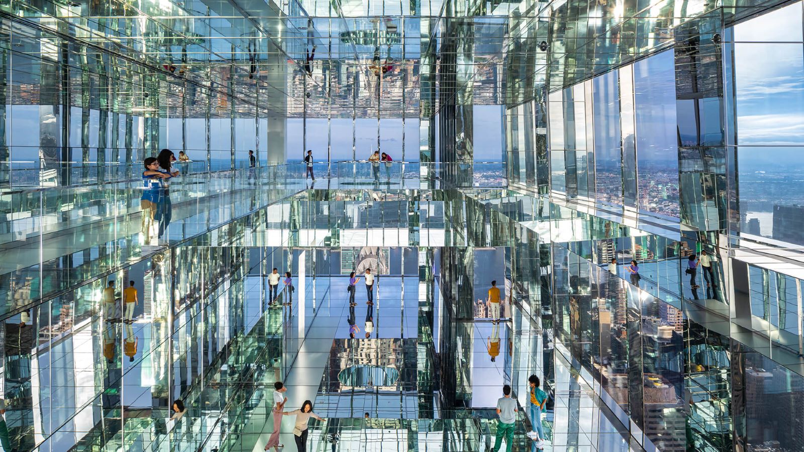 Visitors inside a multi-level mirroed structure with transparent floors, showcasing panoramic city views.